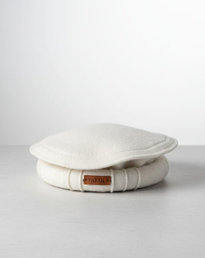 White cushion with a brand label on a light gray background