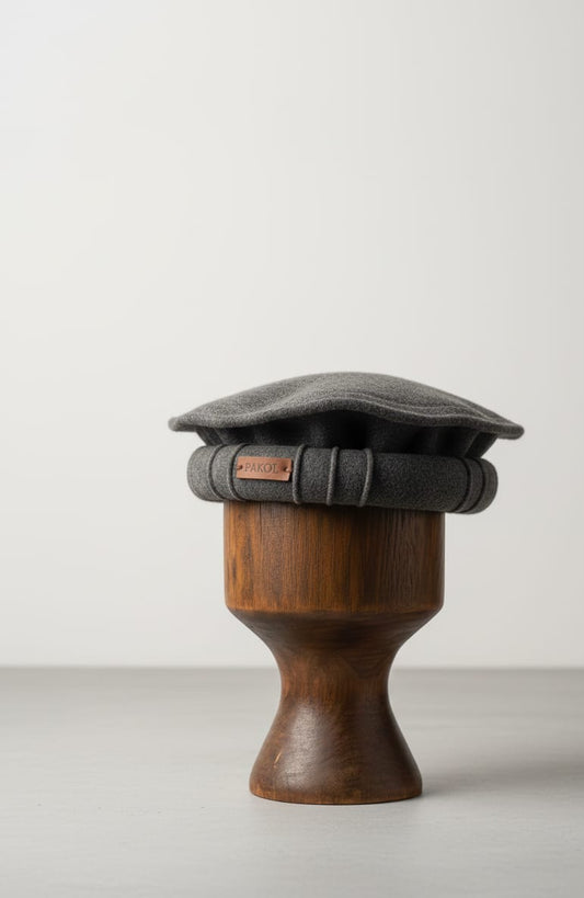 Gray flat cap on a wooden hat stand against a white background